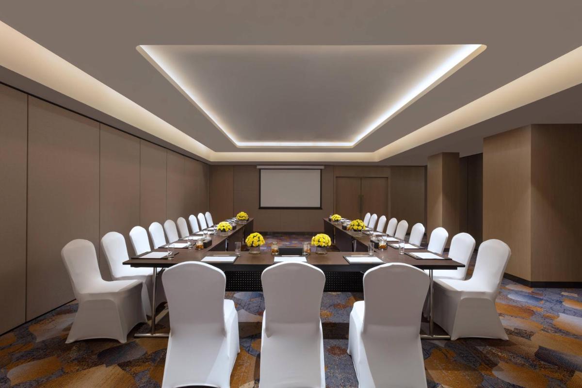 a conference room with a long table and white chairs at Courtyard by Marriott Amritsar in Amritsar