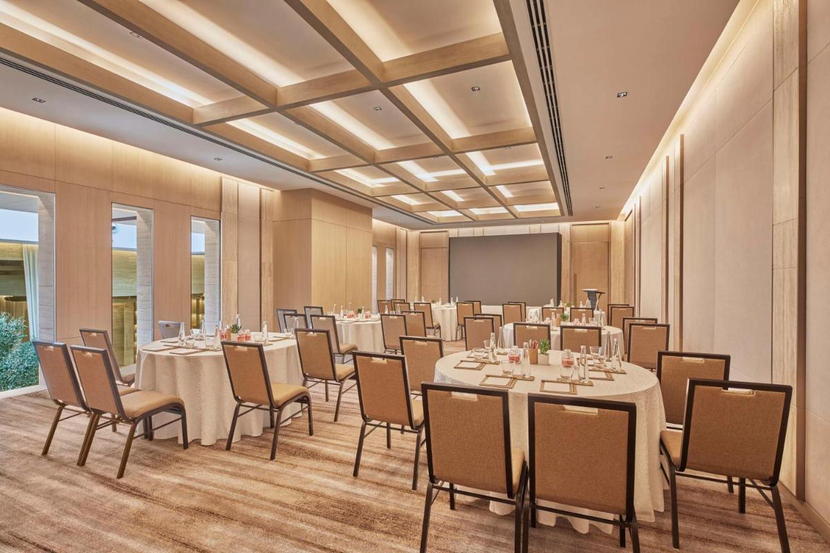 a conference room with tables and chairs and a screen at Hilton Gurugram Baani City Centre in Gurgaon