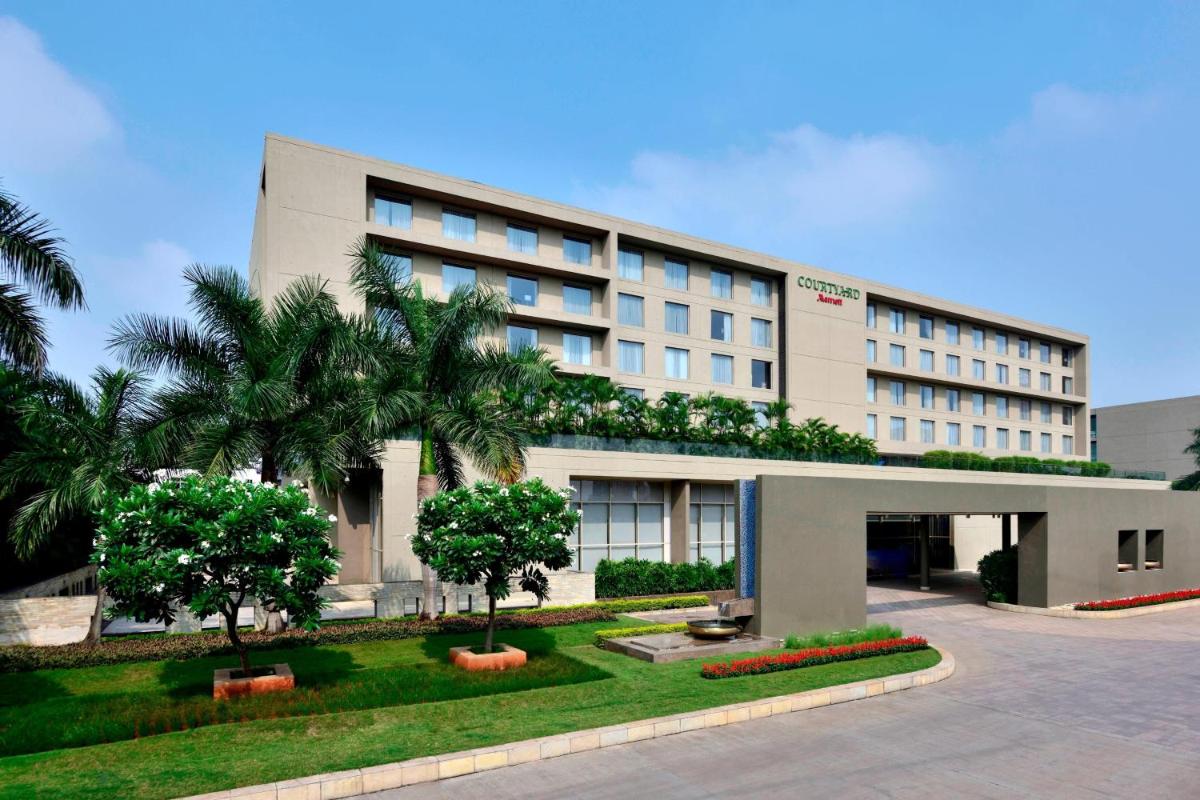 a building with palm trees in front of it at Courtyard by Marriott Pune Hinjewadi in Pune
