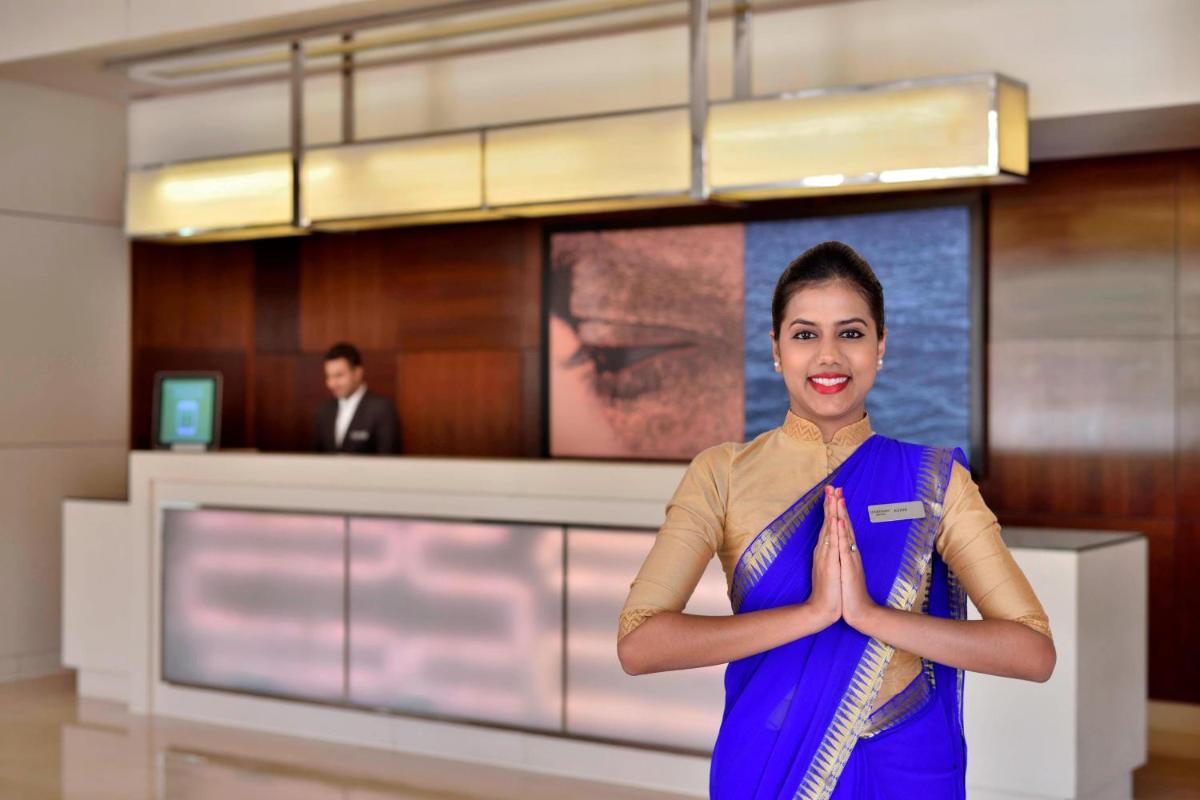 a woman standing in a room with her hands in front at Courtyard by Marriott Pune Hinjewadi in Pune
