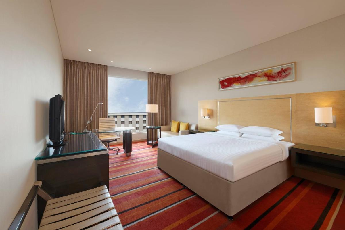 a hotel room with a bed and a flat screen tv at Courtyard by Marriott Pune Hinjewadi in Pune