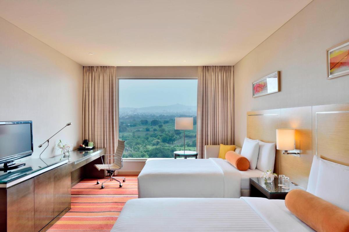 a hotel room with two beds and a large window at Courtyard by Marriott Pune Hinjewadi in Pune