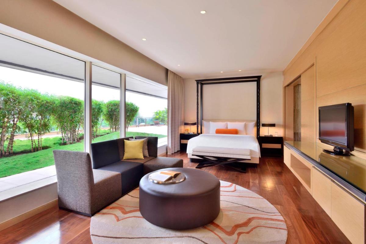 a hotel room with a bed and a couch and a tv at Courtyard by Marriott Pune Hinjewadi in Pune