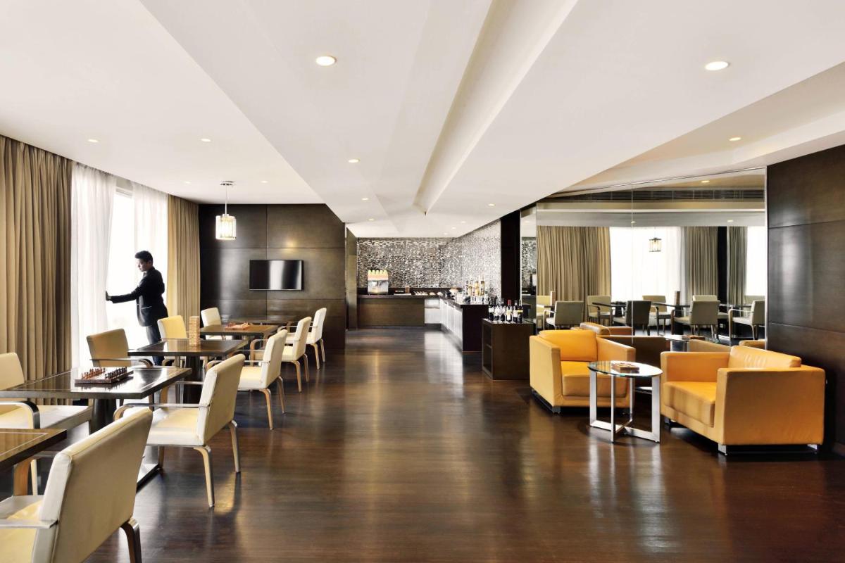 a restaurant with yellow chairs and tables and a man standing at Courtyard by Marriott Pune Hinjewadi in Pune