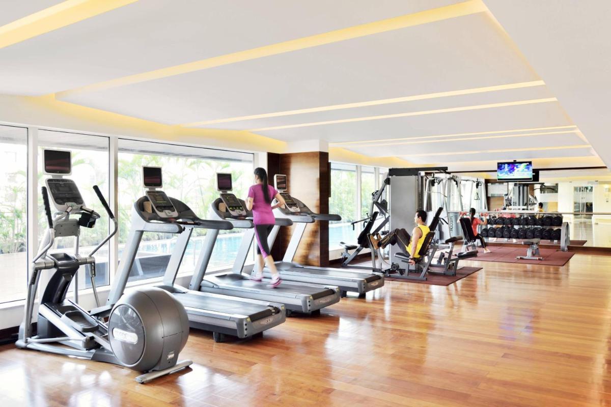 a gym with people exercising on treadmills and machines at Courtyard by Marriott Pune Hinjewadi in Pune