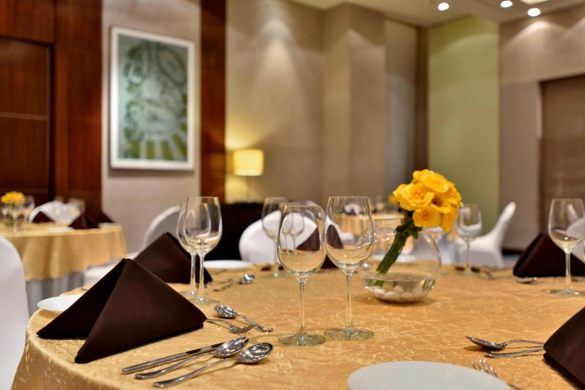 a table with wine glasses and a yellow flower on it at Courtyard by Marriott Pune Hinjewadi in Pune