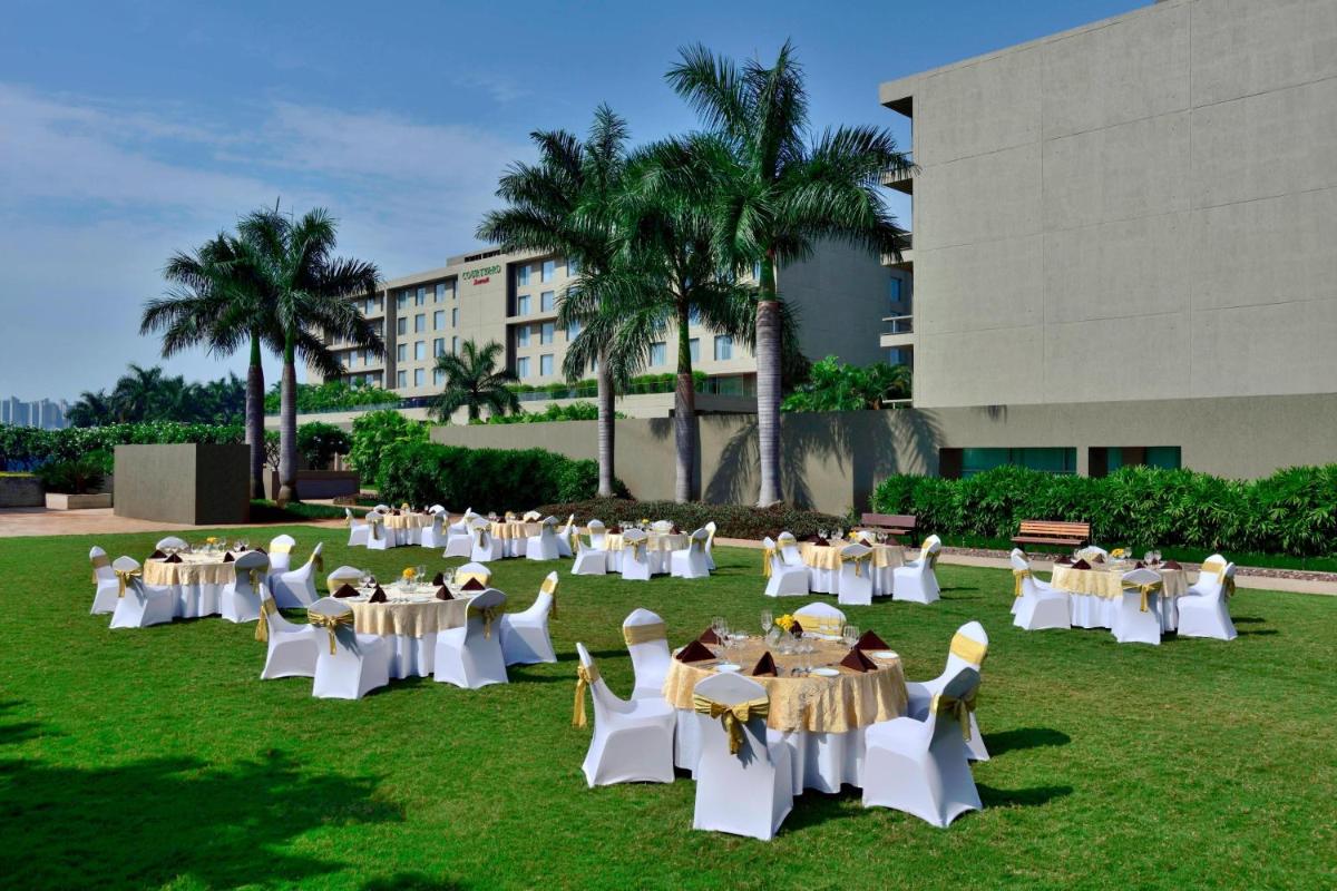 a group of people sitting at tables in the grass at Courtyard by Marriott Pune Hinjewadi in Pune