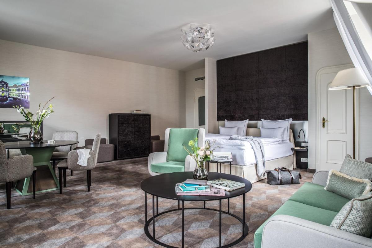 ein Hotelzimmer mit einem Bett und einem Tisch und Stühlen in der Unterkunft Gewandhaus Dresden, Autograph Collection in Dresden