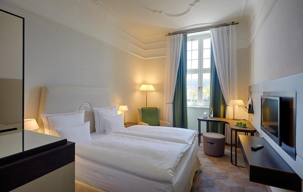 ein Hotelzimmer mit einem Bett und einem Fernseher in der Unterkunft Gewandhaus Dresden, Autograph Collection in Dresden