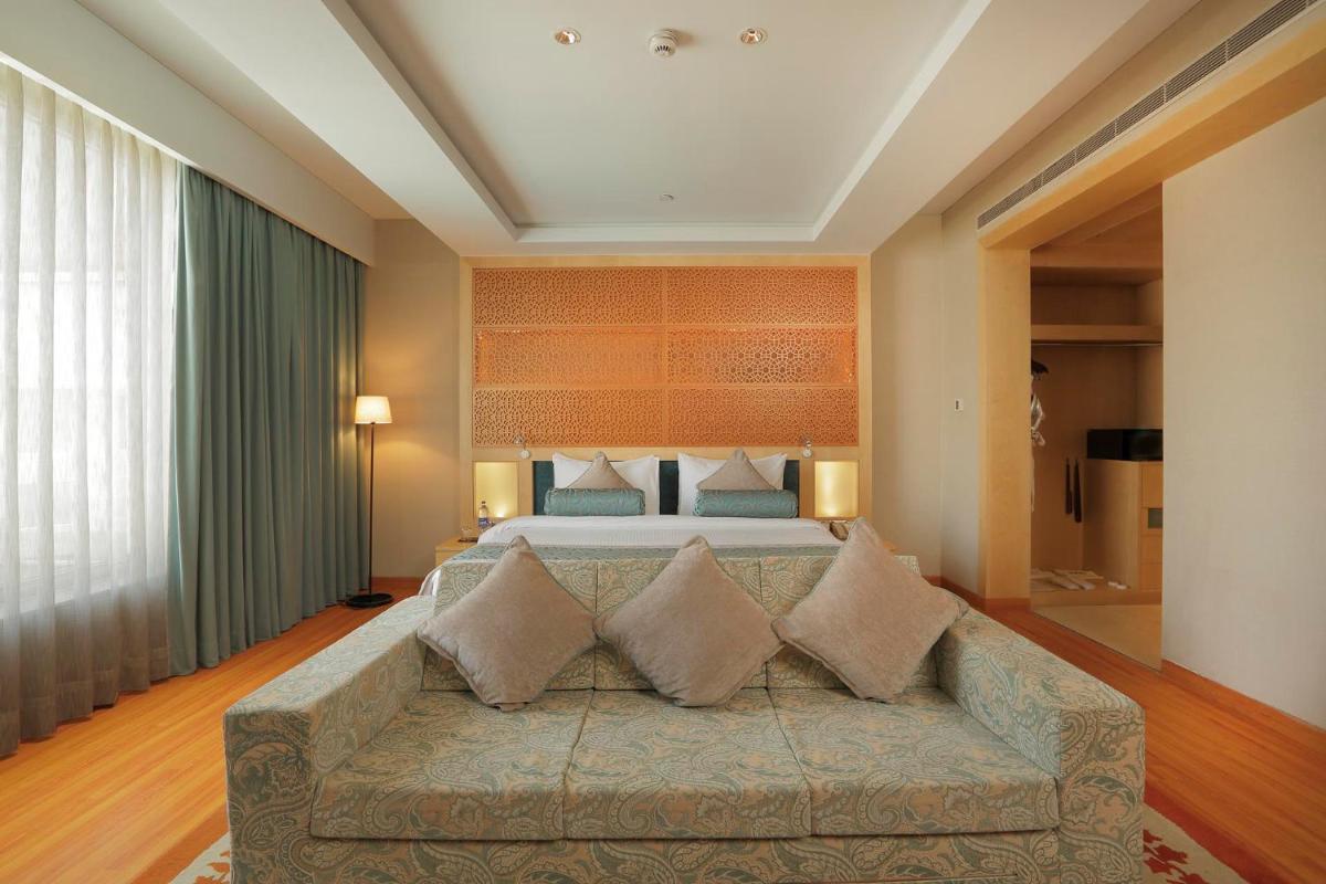 a living room with a couch in front of a bed at Yashail Hotel Haridwar in Haridwār