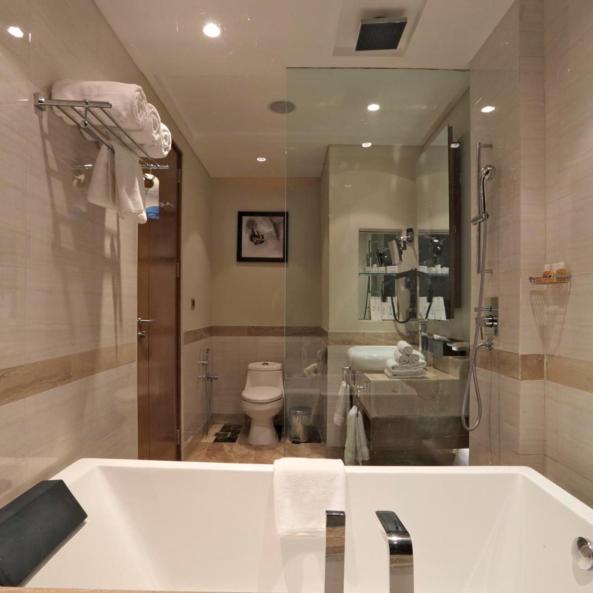 a bathroom with a tub and a toilet and a mirror at Yashail Hotel Haridwar in Haridwār