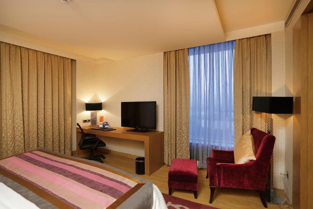 a hotel room with a bed and a desk and a television at Yashail Hotel Haridwar in Haridwār