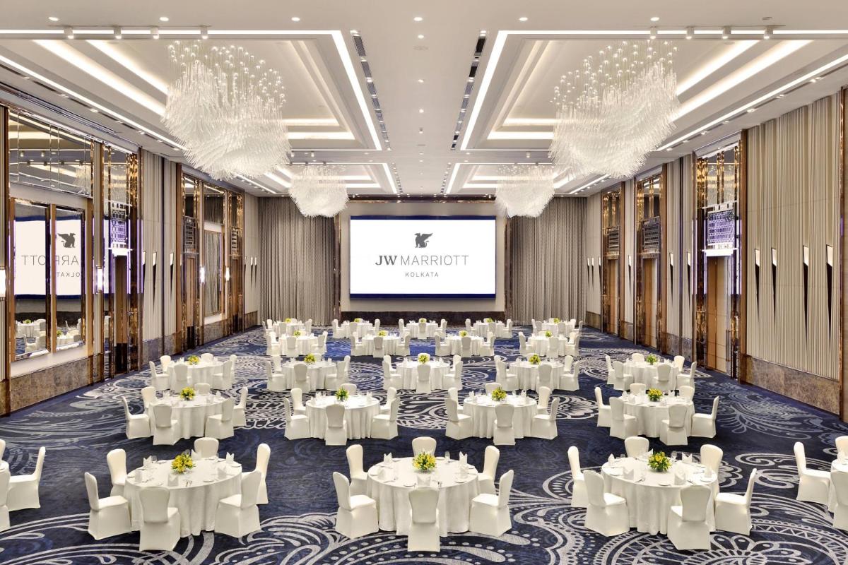 a ballroom with tables and chairs and a projection screen at JW Marriott Hotel Kolkata in Kolkata