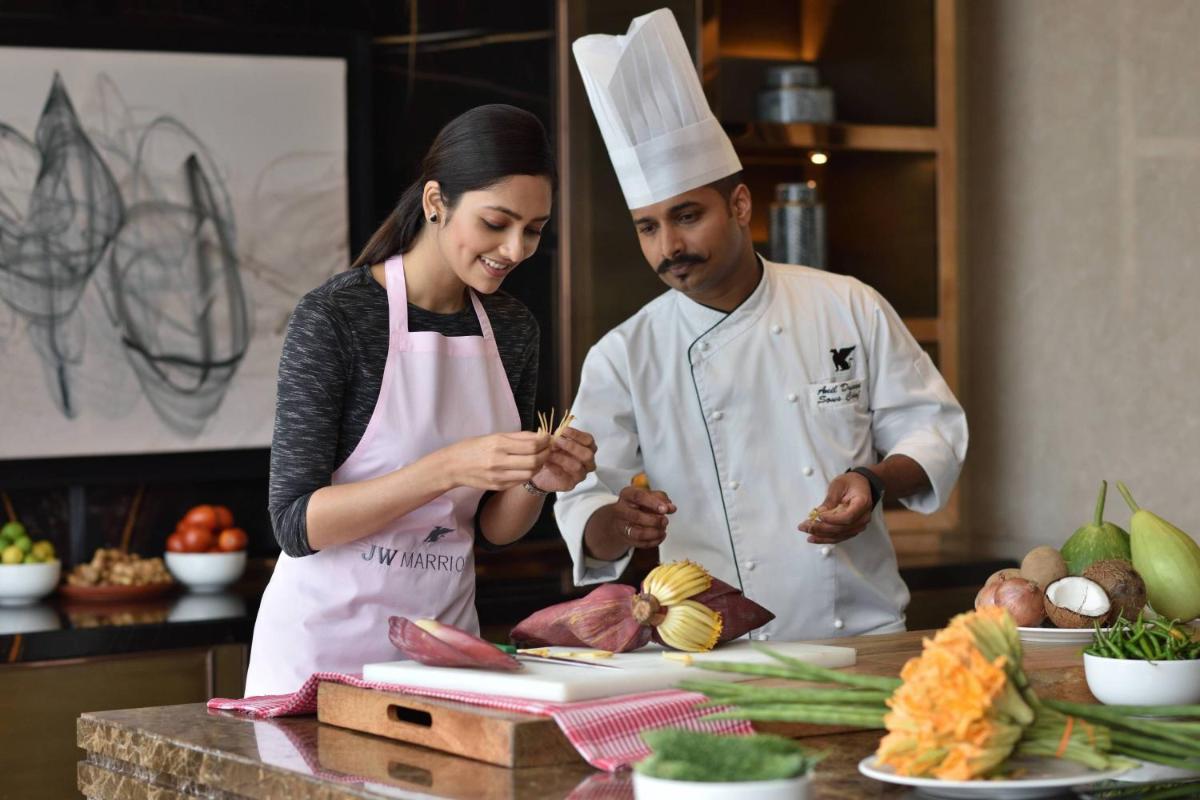 a man and woman in a kitchen preparing food at JW Marriott Hotel Kolkata in Kolkata