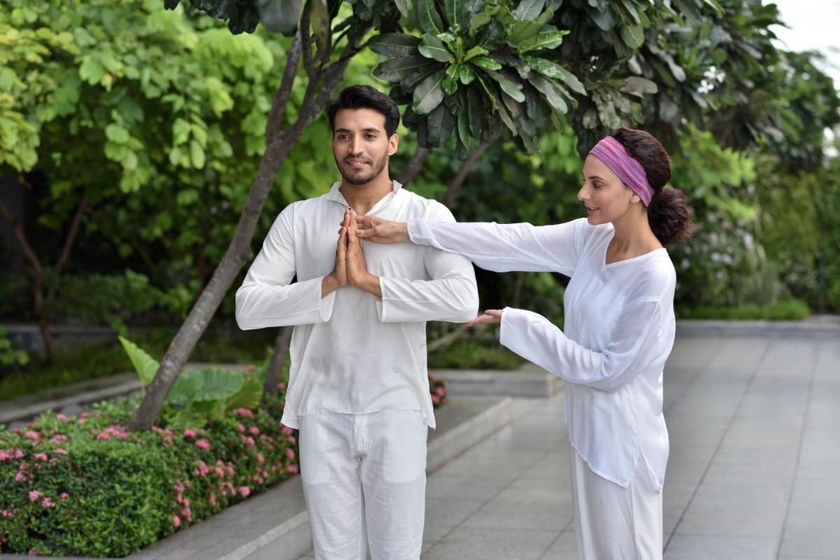 a man and a woman in white outfit tying a tie at JW Marriott Hotel Kolkata in Kolkata