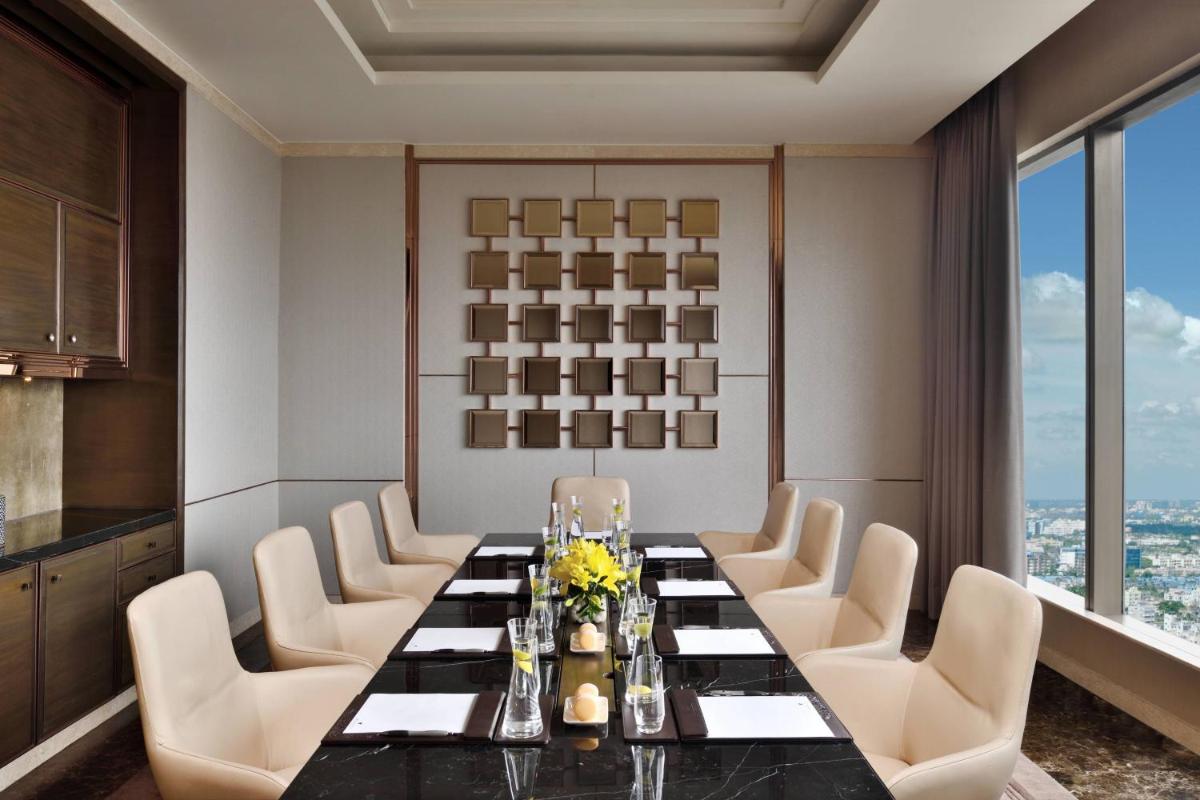 a dining room with a long table and white chairs at JW Marriott Hotel Kolkata in Kolkata