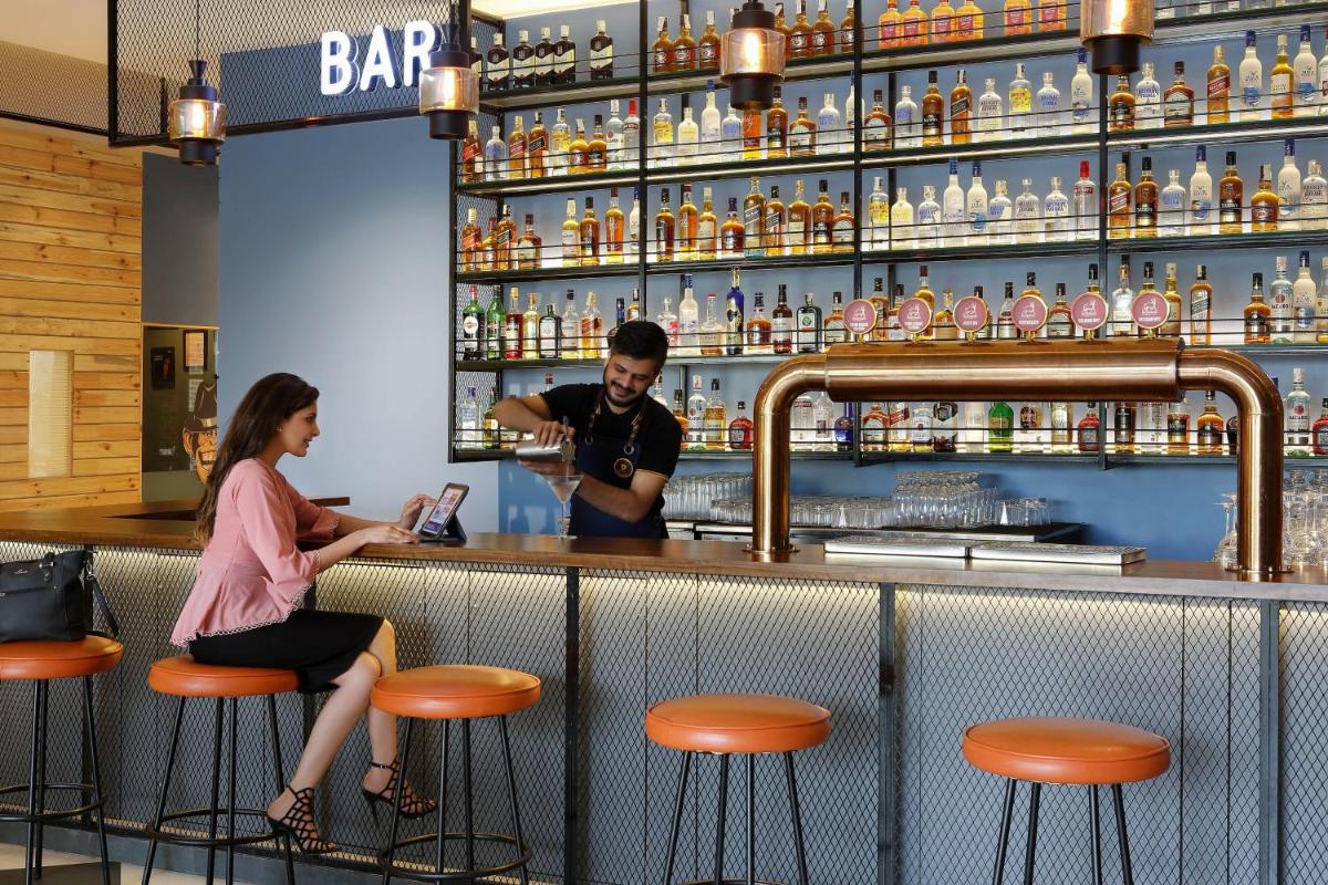 a man and a woman sitting at a bar at Four Points by Sheraton Hotel and Serviced Apartments Pune in Pune