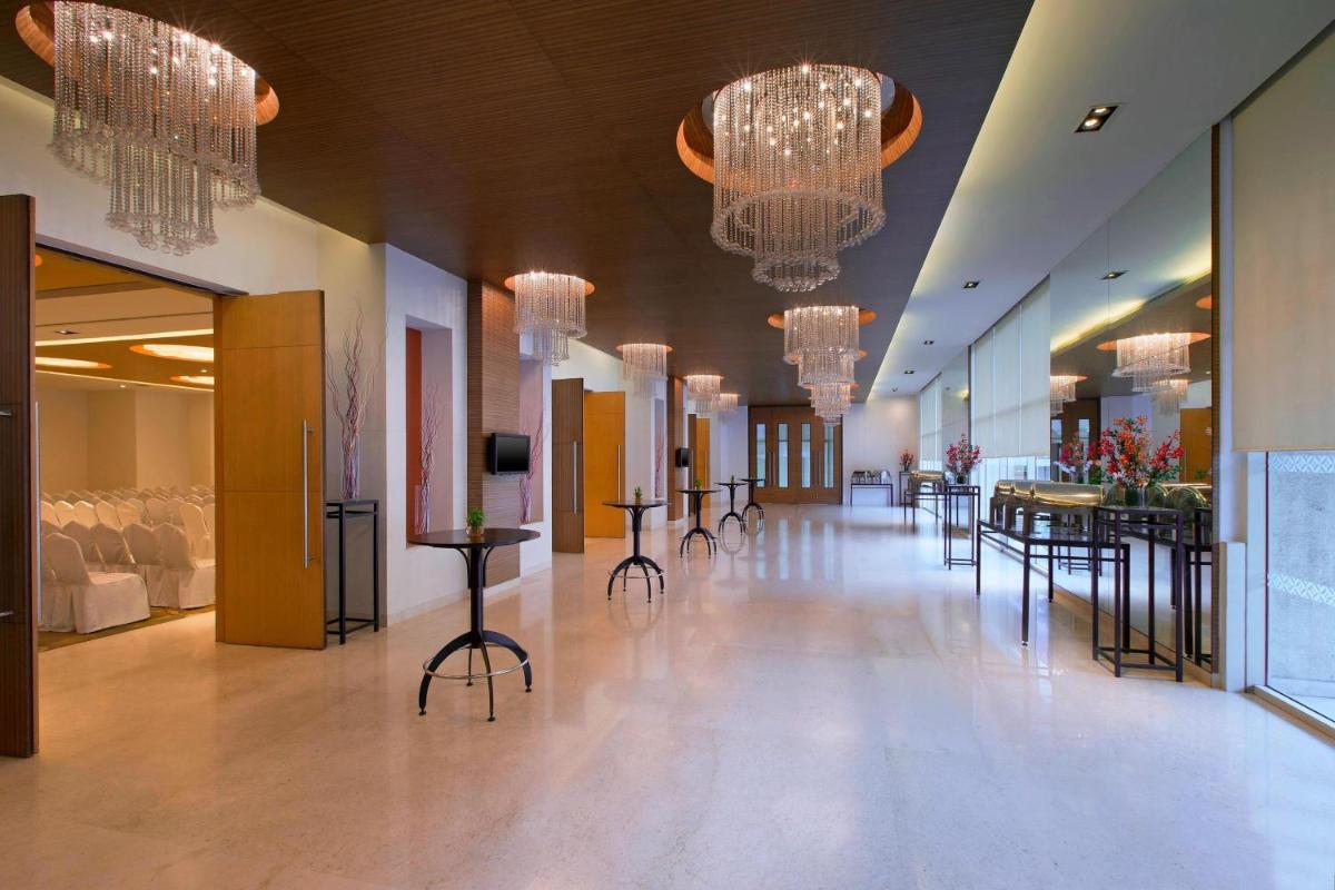 a hallway with chandeliers and tables in a building at Four Points by Sheraton Hotel and Serviced Apartments Pune in Pune