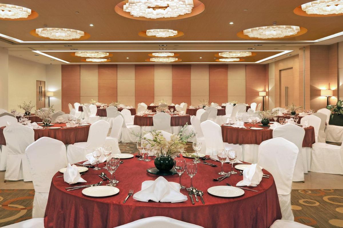a banquet hall with tables and white chairs at Four Points by Sheraton Hotel and Serviced Apartments Pune in Pune