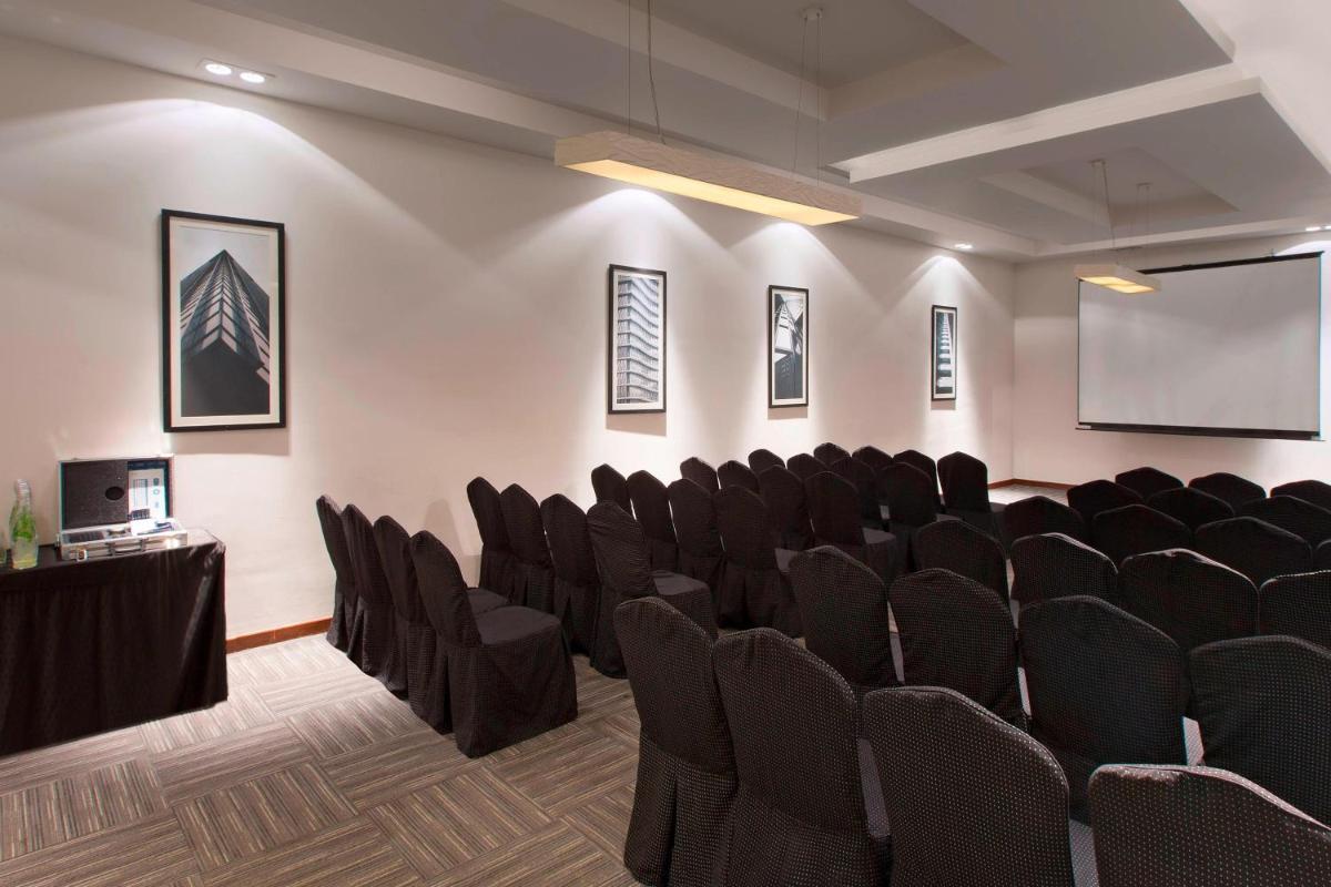 a conference room with black chairs and a screen at Four Points by Sheraton Hotel and Serviced Apartments Pune in Pune