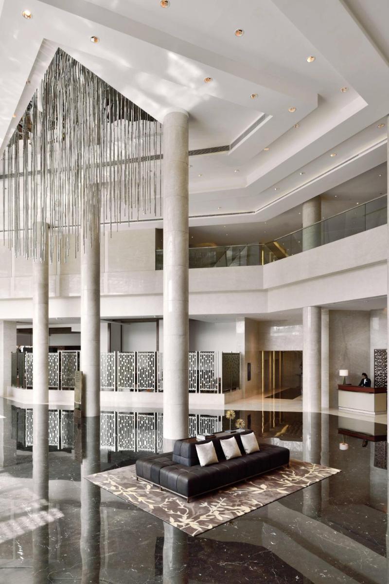 a lobby with a black couch and a chandelier at Kochi Marriott Hotel in Cochin
