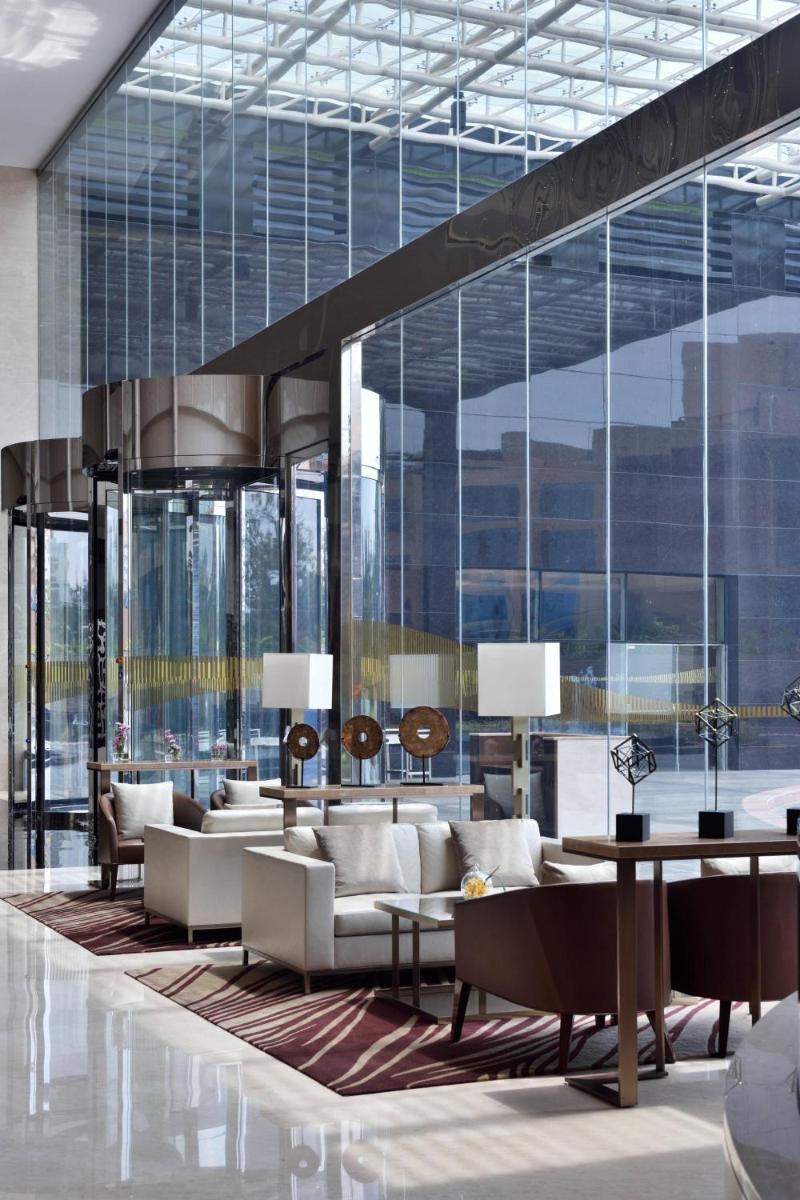a lobby with white furniture and large windows at Kochi Marriott Hotel in Cochin