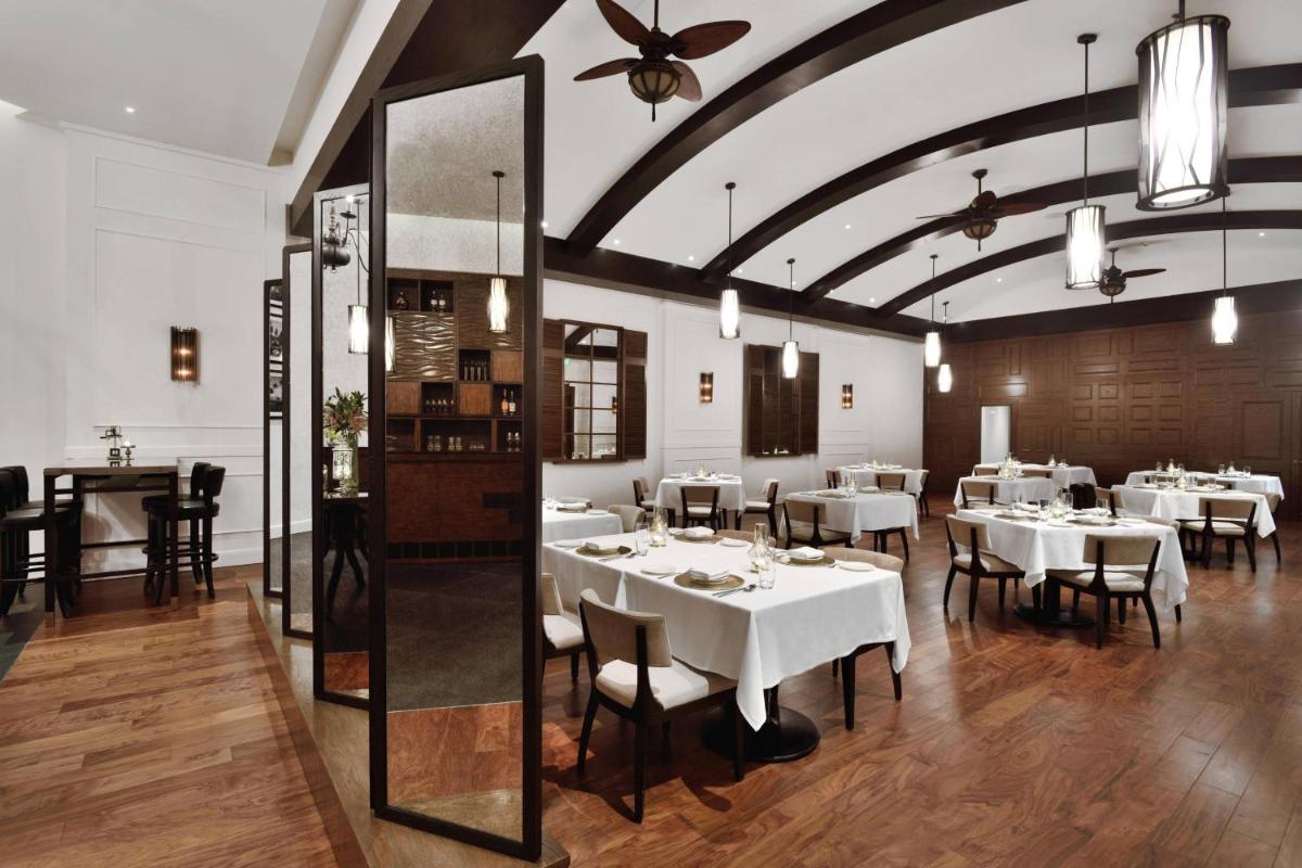 a restaurant with white tables and chairs in a room at Kochi Marriott Hotel in Cochin