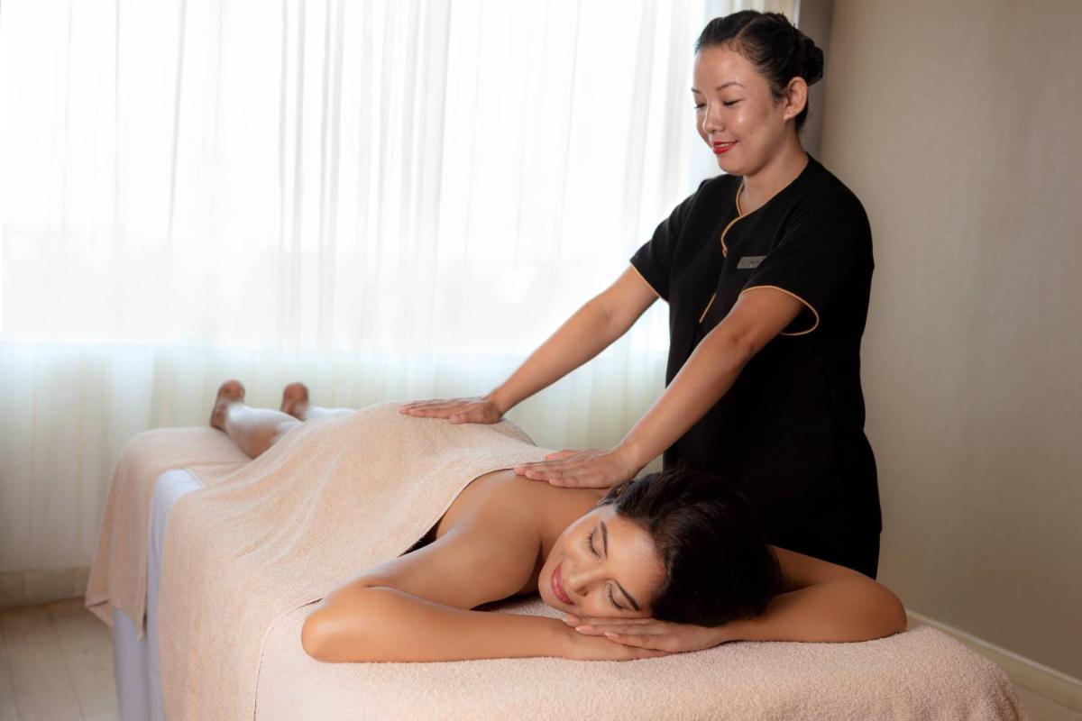a woman laying on a bed while a woman is getting acupuncture at Kochi Marriott Hotel in Cochin
