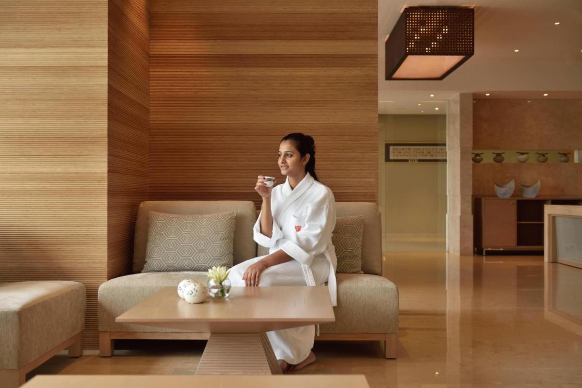 a woman in a white robe sitting on a couch at Kochi Marriott Hotel in Cochin