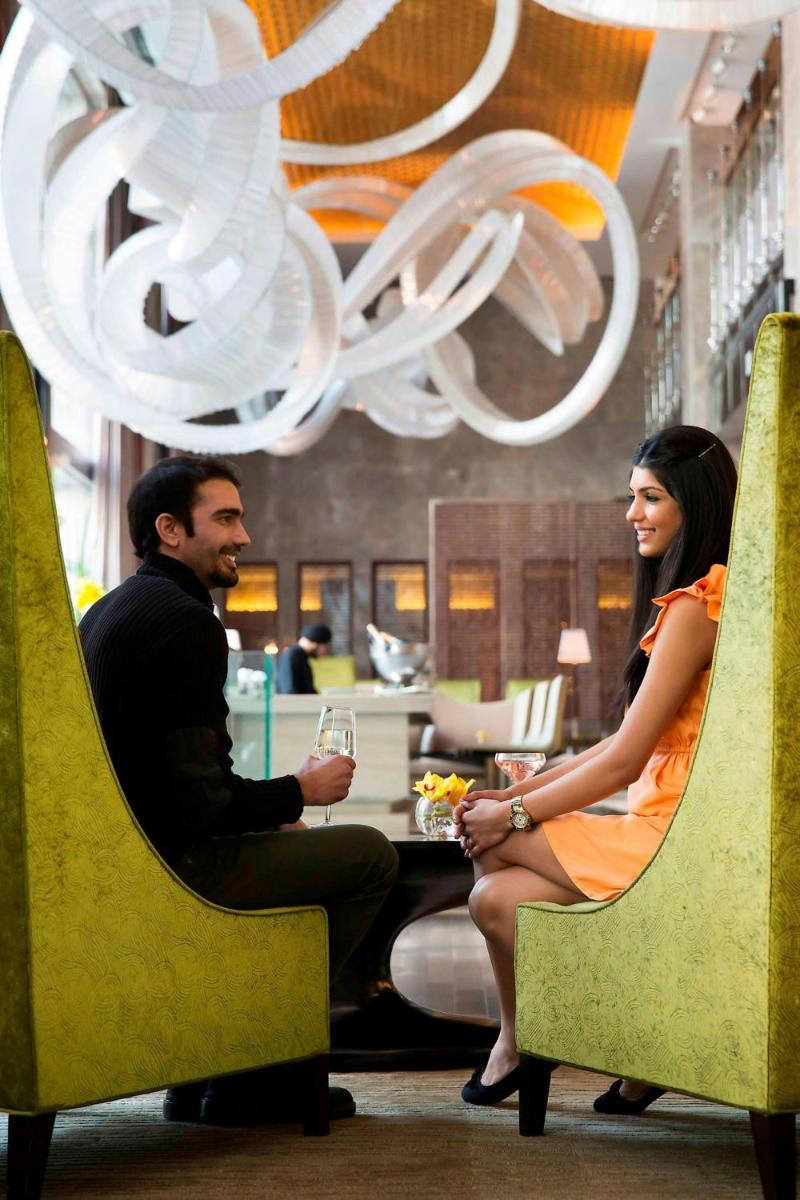 a man and woman sitting in chairs in a restaurant at JW Marriott Hotel New Delhi Aerocity in New Delhi a man and woman sitting in chairs in a restaurant at JW Marriott Hotel New Delhi Aerocity in New Delhi