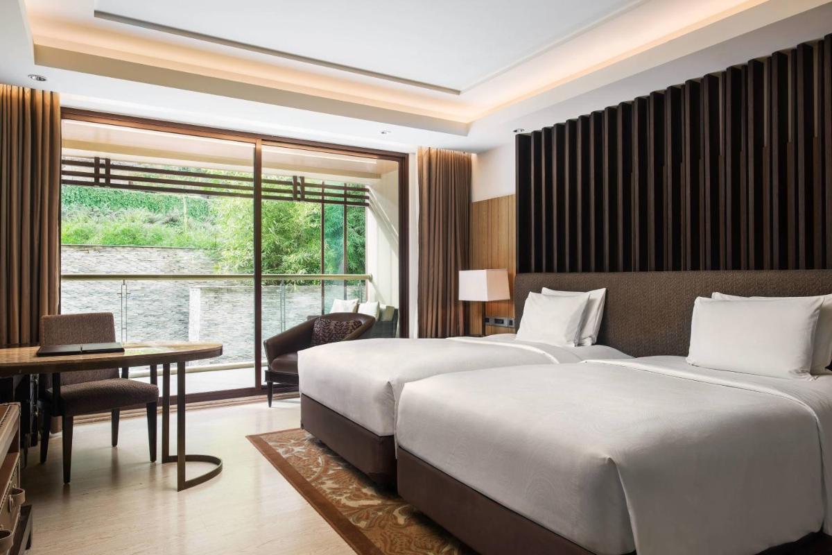 a bedroom with two beds and a desk and a window at JW Marriott Mussoorie Walnut Grove Resort & Spa in Mussoorie