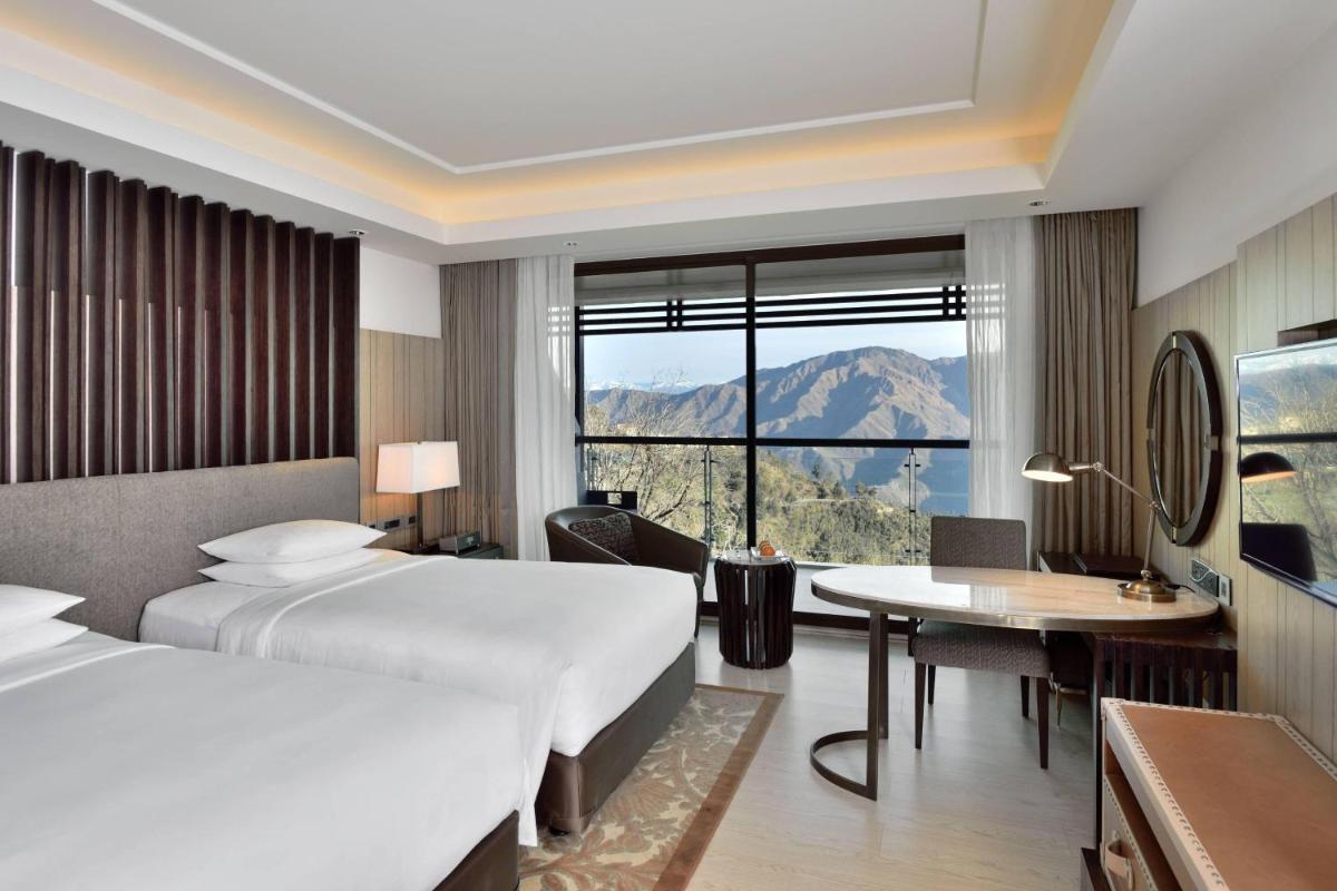 a hotel room with two beds and a desk at JW Marriott Mussoorie Walnut Grove Resort & Spa in Mussoorie