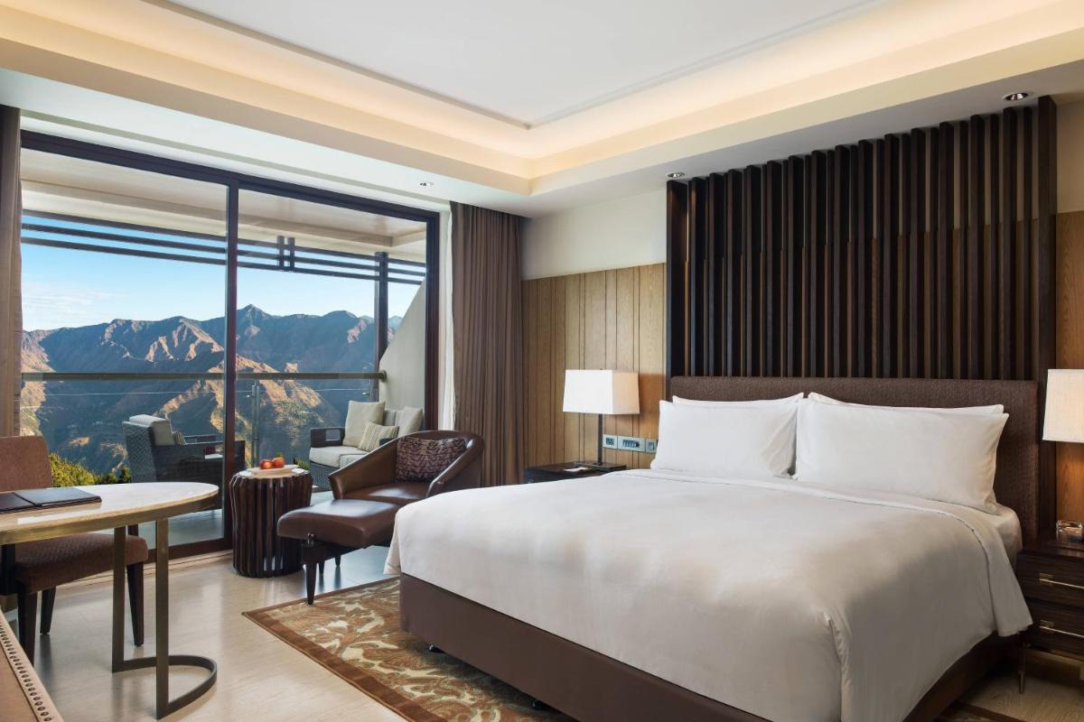 a bedroom with a bed and a living room with a view at JW Marriott Mussoorie Walnut Grove Resort & Spa in Mussoorie