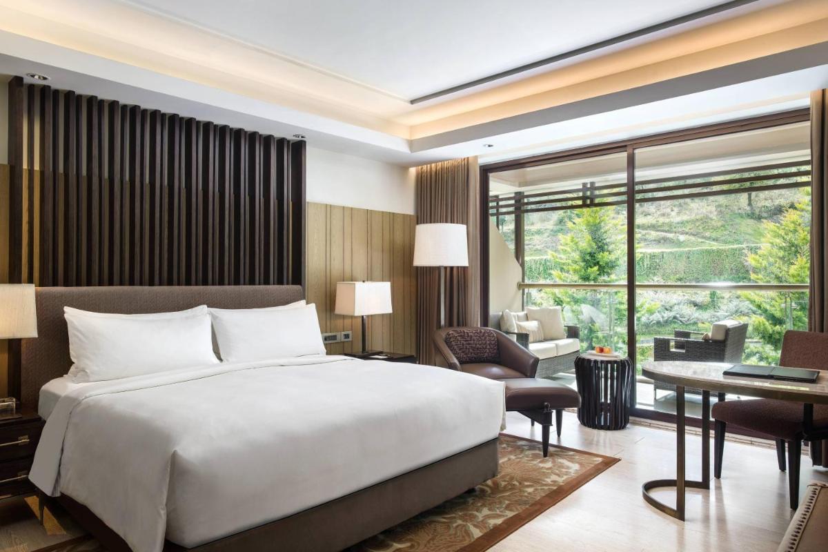 a bedroom with a bed and a living room with a desk at JW Marriott Mussoorie Walnut Grove Resort & Spa in Mussoorie