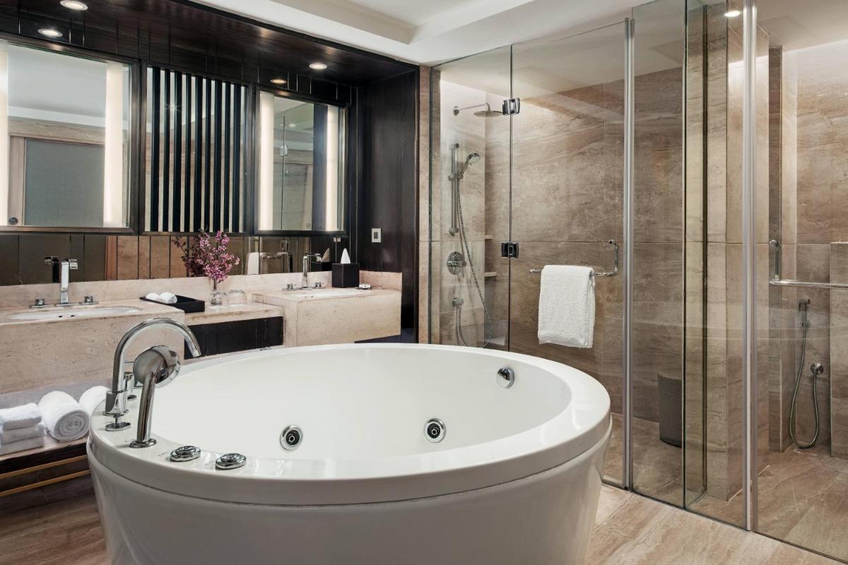 a bathroom with a tub and a glass shower at JW Marriott Mussoorie Walnut Grove Resort & Spa in Mussoorie