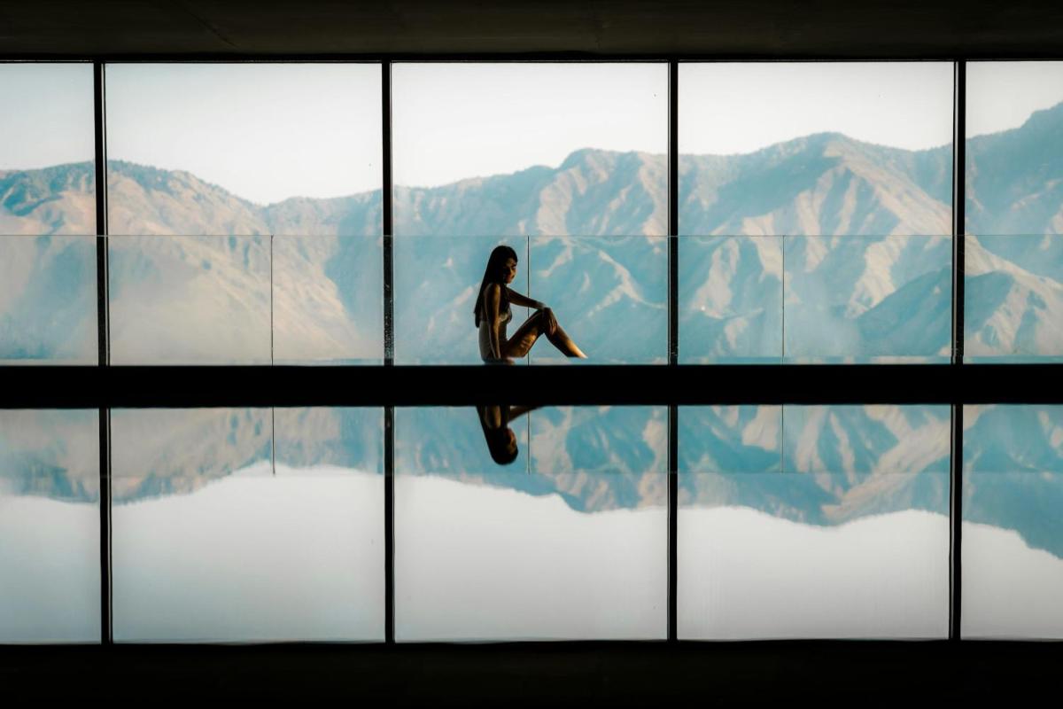 a woman sitting on a window looking at the mountains at JW Marriott Mussoorie Walnut Grove Resort & Spa in Mussoorie