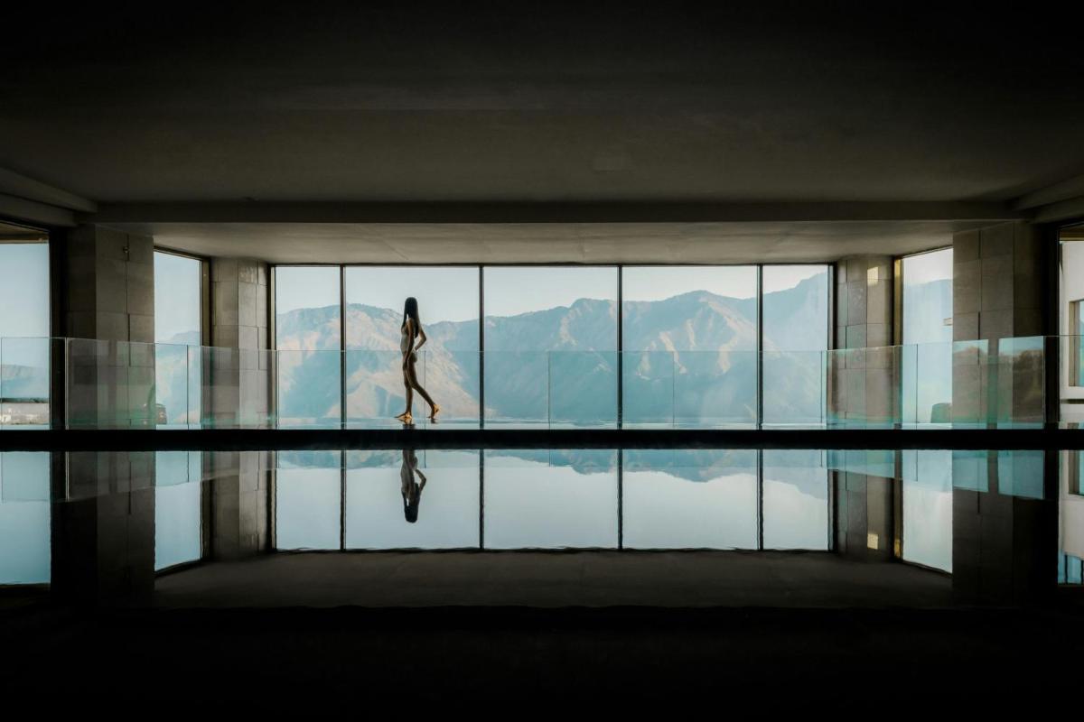 a woman walking in a building with a pool of water at JW Marriott Mussoorie Walnut Grove Resort & Spa in Mussoorie