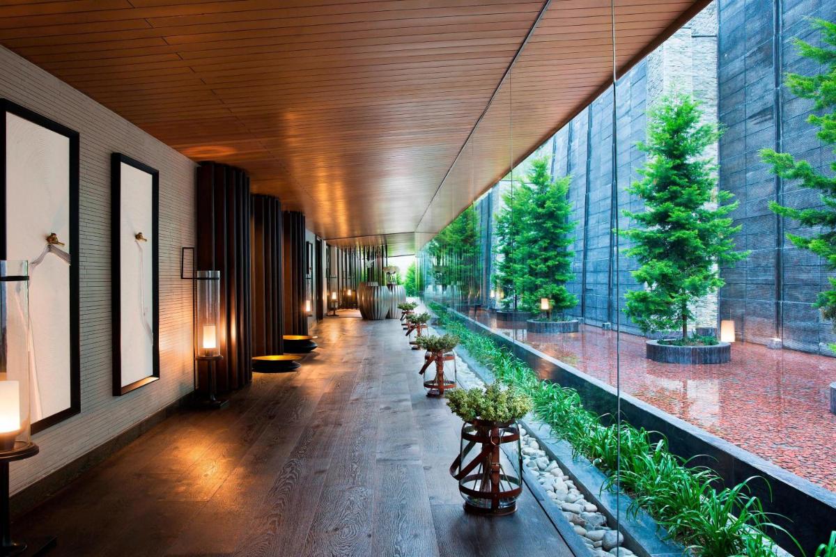 a hallway of a building with plants on the floor at JW Marriott Mussoorie Walnut Grove Resort & Spa in Mussoorie
