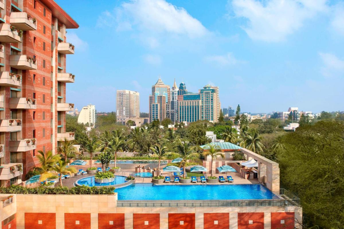 a view of the pool at a resort with a city at ITC Gardenia, a Luxury Collection Hotel, Bengaluru in Bengaluru a view of the pool at a resort with a city at ITC Gardenia, a Luxury Collection Hotel, Bengaluru in Bengaluru