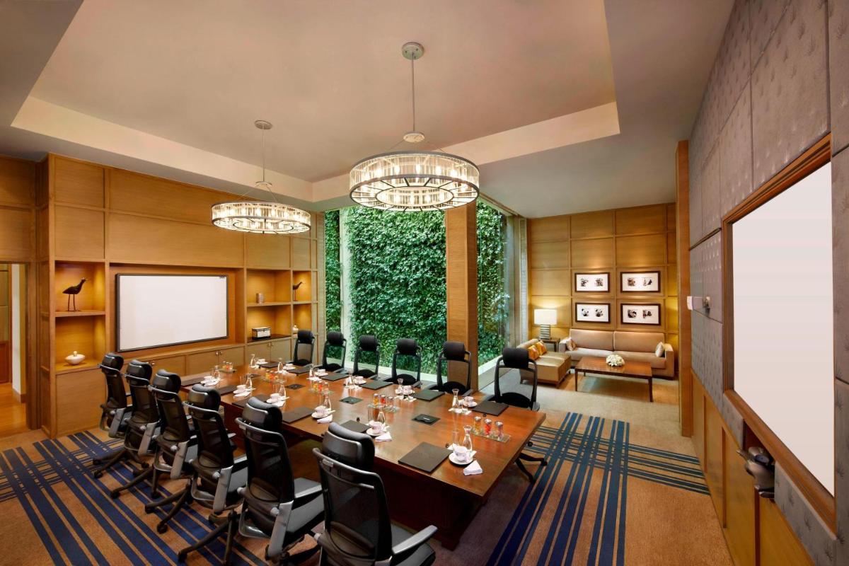 a conference room with a long table and chairs at ITC Gardenia, a Luxury Collection Hotel, Bengaluru in Bengaluru a conference room with a long table and chairs at ITC Gardenia, a Luxury Collection Hotel, Bengaluru in Bengaluru
