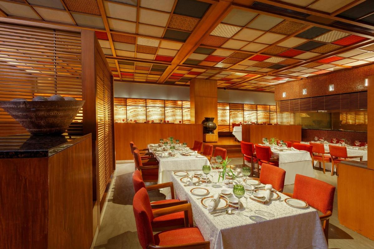 a dining room with white tables and red chairs at ITC Sonar, a Luxury Collection Hotel, Kolkata in Kolkata