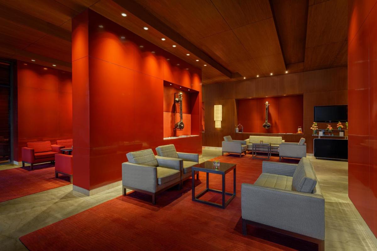 a lobby with red walls and chairs and tables at ITC Sonar, a Luxury Collection Hotel, Kolkata in Kolkata