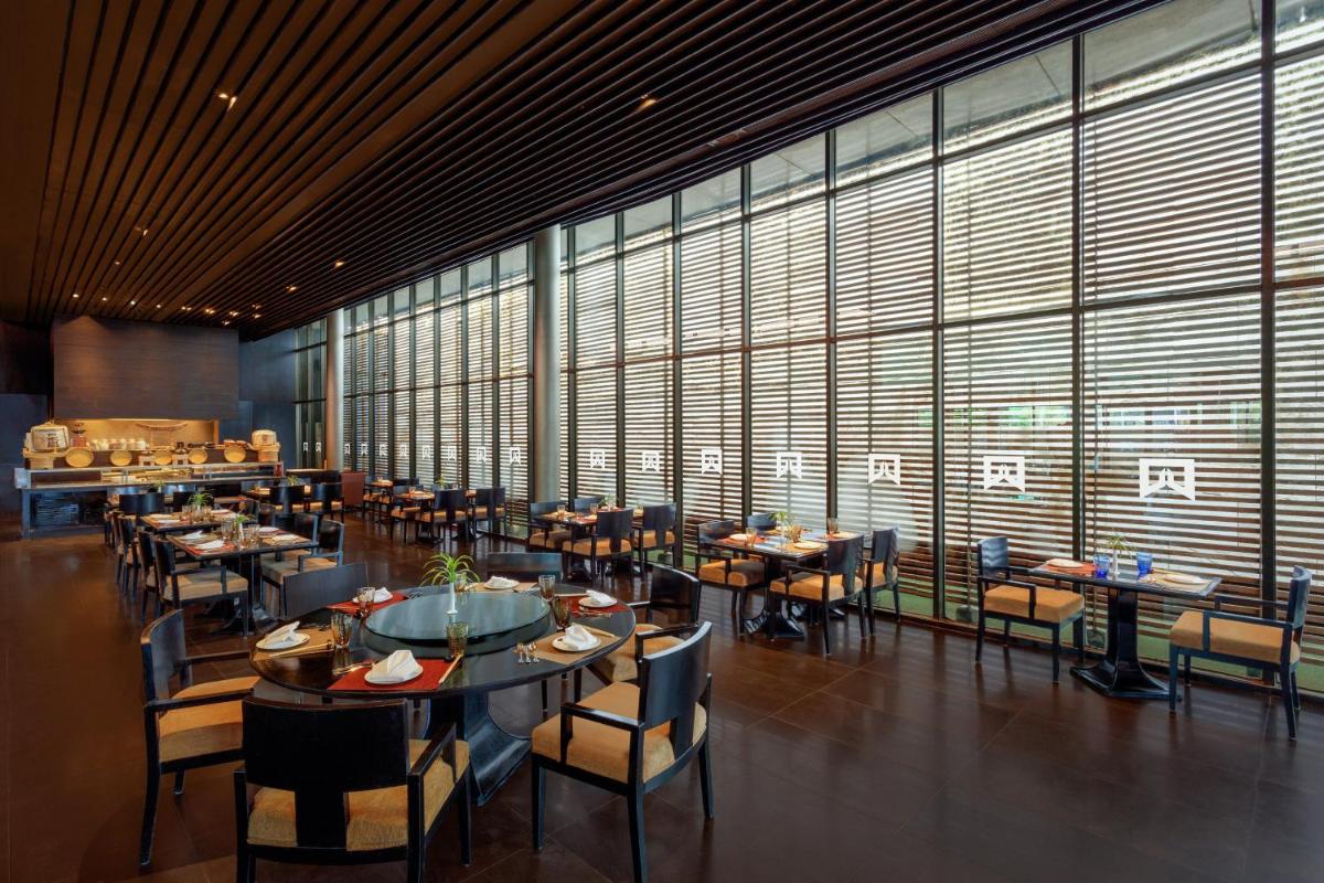 a dining room with tables and chairs and large windows at ITC Sonar, a Luxury Collection Hotel, Kolkata in Kolkata