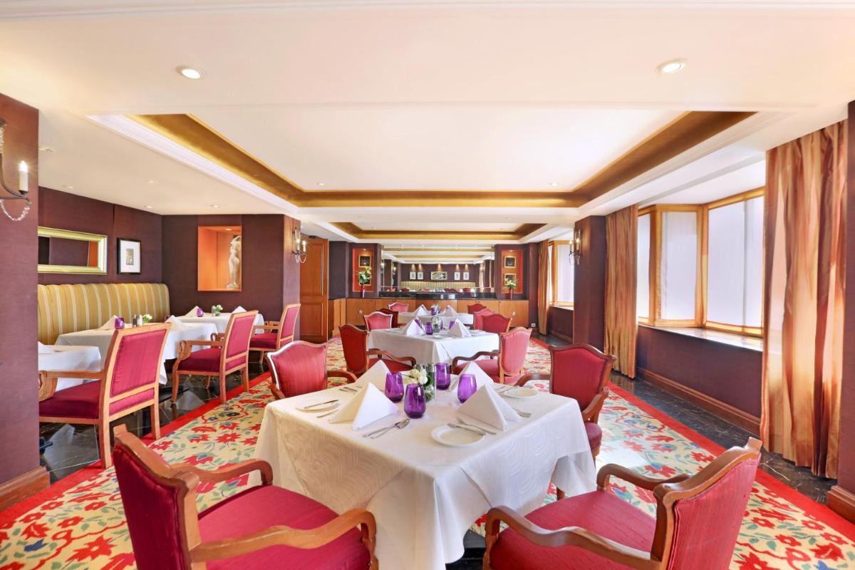 a restaurant with white tables and red chairs at ITC Maratha, a Luxury Collection Hotel, Mumbai in Mumbai