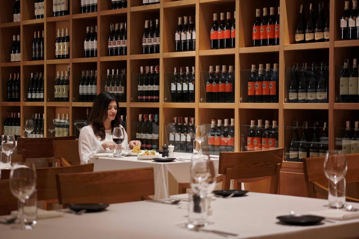 a woman sitting at a table in a wine cellar at Marriott Suites Pune in Pune
