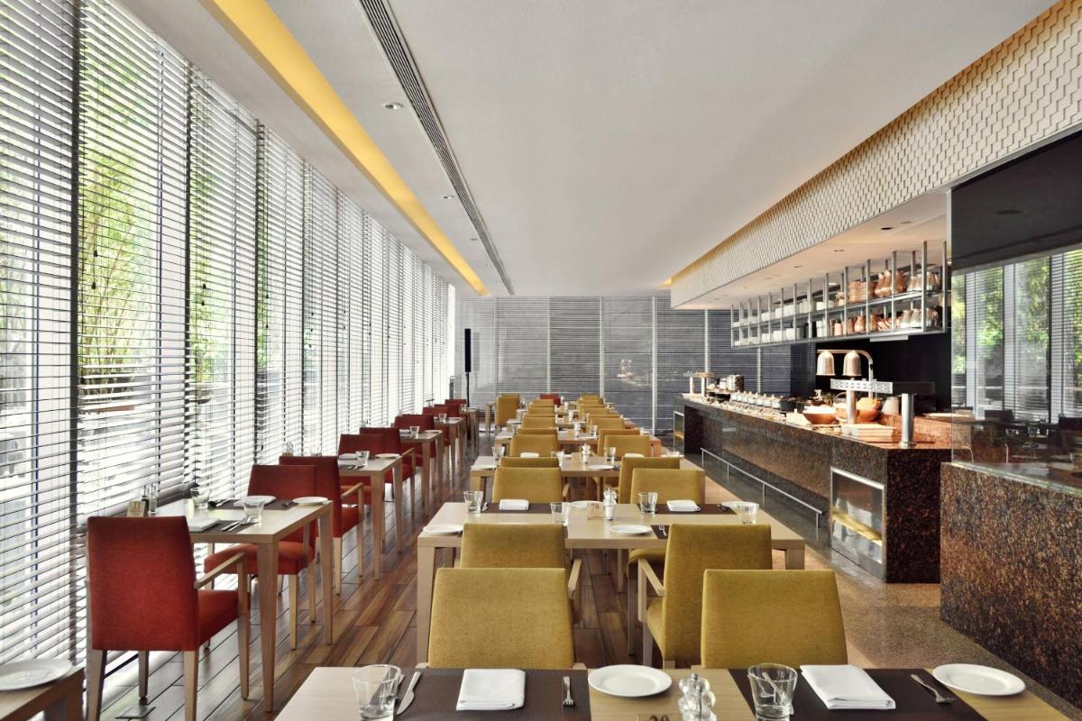 a dining room with tables and chairs and windows at Marriott Suites Pune in Pune