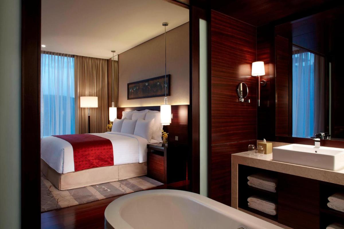 a bathroom with a bed and a tub and a sink at JW Marriott Pune in Pune