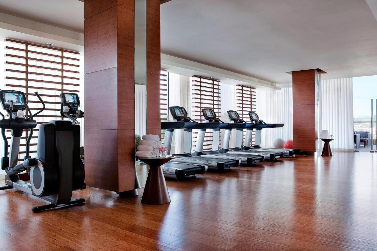 a gym with a row of treadmills and a large room at JW Marriott Pune in Pune