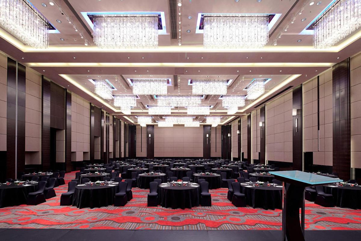 a large banquet hall with black tables and chandeliers at JW Marriott Pune in Pune