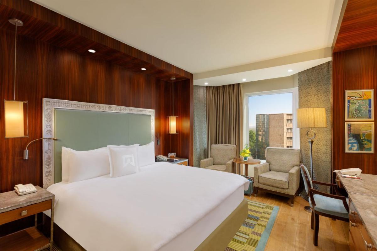 a bedroom with a large white bed and a desk at ITC Maurya, a Luxury Collection Hotel, New Delhi in New Delhi a bedroom with a large white bed and a desk at ITC Maurya, a Luxury Collection Hotel, New Delhi in New Delhi